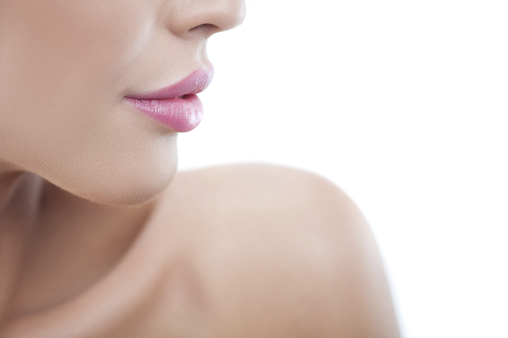 Close up of lips of pretty girl expressing her sensuality. She is standing with naked shoulder. Isolated and copy space in right side